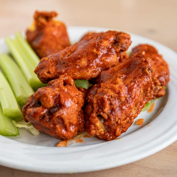 A plate of Cornerstone Cafe & Bar's buffalo wings with celery sticks and lettuce.